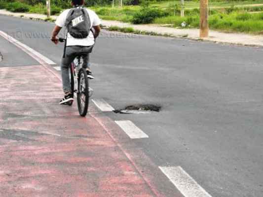Ciclista desvia de desnível em asfalto na Tancredo Neves