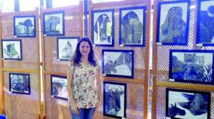 A bióloga e ilustradora Patrícia Milano com algumas de suas obras, que ilustram animais de pequeno e grande portes