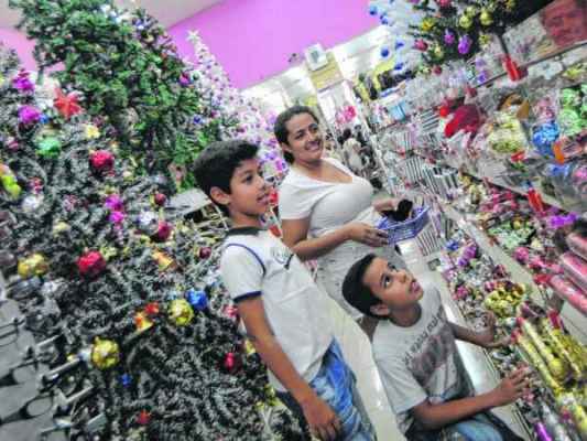 Hosana Nunes de Freitas e os filhos André (de pé) e Davi escolhem produtos de Natal em loja estabelecida na Rua 3, Centro