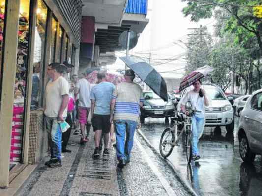 Os consumidores caminhavam sob chuva na Rua 4 na tarde dessa terça-feira (23). As lojas abrem hoje das 9 às 18 horas