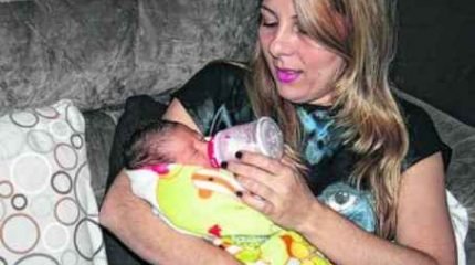 Na foto, Karina segura a pequena Laura em seus braços e comemora a chegada de sua filha através da “barriga solidária”