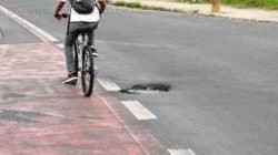 Ciclista desvia de desnível em asfalto na Tancredo Neves