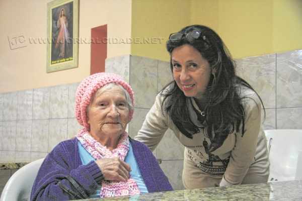 Voluntária ao lado de Dona Ambrosia, 96 anos de idade, que está no abrigo há 16 anos