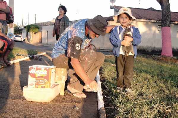 Sergio Rampin dá os últimos retoques de tinta branca em uma das guias da pracinha localizada na Rua 9-A, com a Rua 19