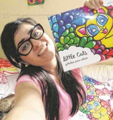 A artista Joana Diggle segura um exemplar do seu livro ‘Little Cats’- Gatinhos Para Colorir