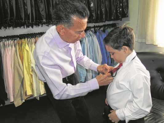 O pequeno Luis Henrique Grego Firmano, de 7 anos, recebe a ajuda de Augusto ao experimentar roupa para um casamento