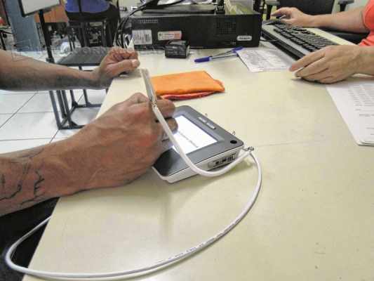 Eleitor faz assinatura digital durante atendimento para o cadastramento biométrico