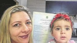 A mãe Karina Freschi segura a certidão de nascimento ao lado da filha, Laura Freschi da Silva