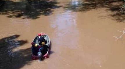 Corpo de Bombeiros trabalha com três homens na água e um barco durante as buscas pelo jovem