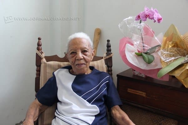 Dona Benedicta Trindade Lopes, de 102 anos de idade, mora com a família, mas a casa vive cheia de amigos e parentes queridos