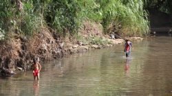Jovens passam pelo Córrego da Servidão, em trecho localizado na Avenida Visconde do Rio Claro