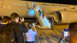 Desembarque dos primeiros brasileiros repatriados na Base Aérea de Brasília: bandeira nacional em punho, em segurança. Foto: Vinicius Neves / Secom / PR