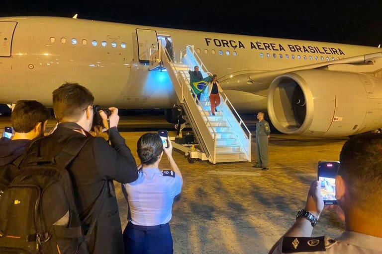 Desembarque dos primeiros brasileiros repatriados na Base Aérea de Brasília: bandeira nacional em punho, em segurança. Foto: Vinicius Neves / Secom / PR