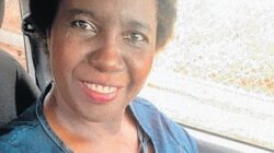 Mulher negra sorrindo dentro de um carro.